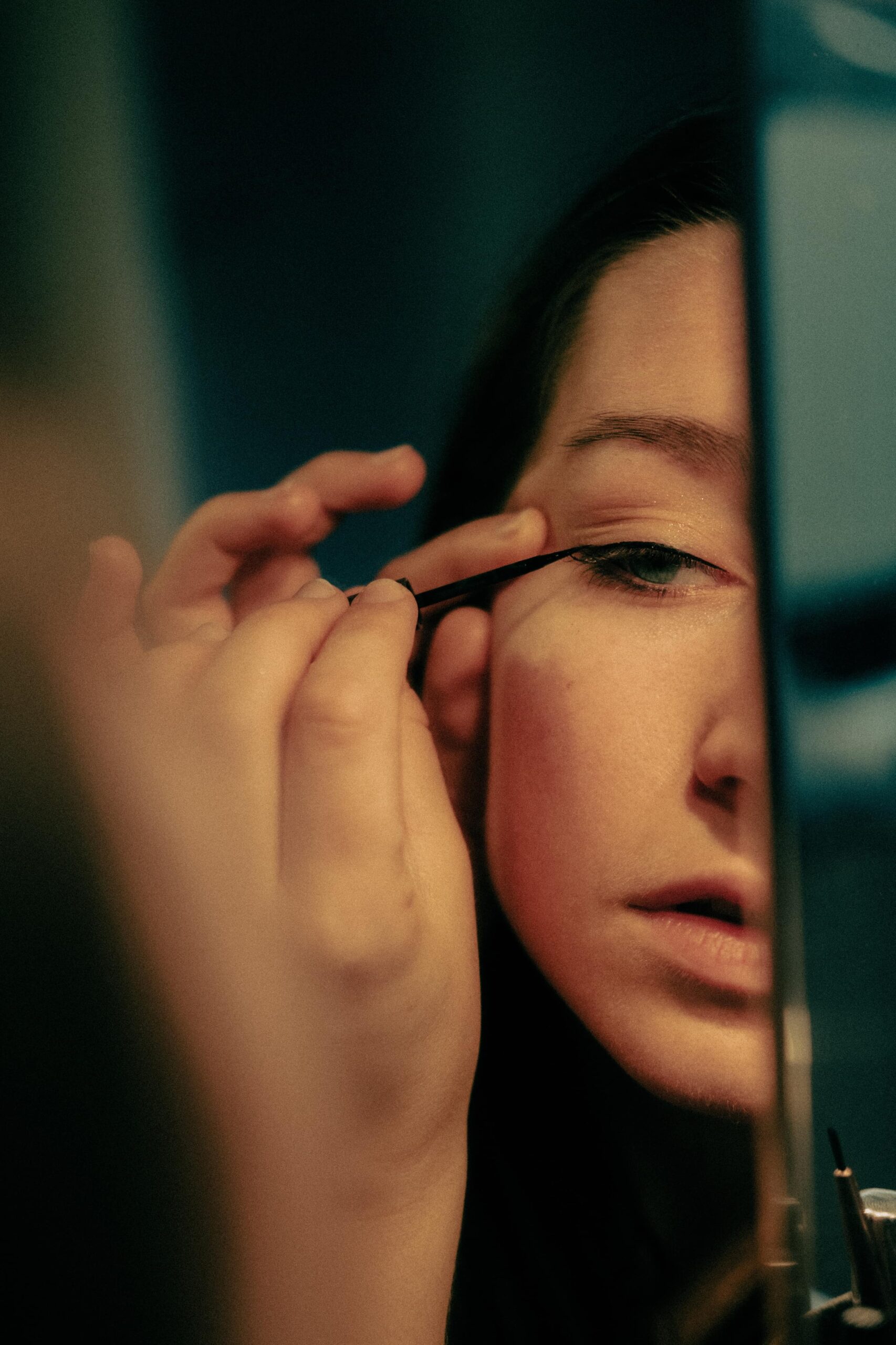 girl applying eyeliner on mirror